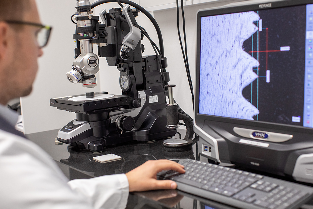 A laboratory technician analyzes the thickness under a microscope